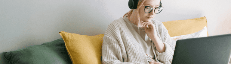woman attending webinar on computer and taking notes